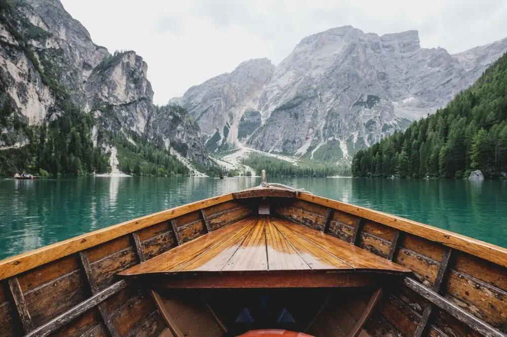 Wooden boat on an alpine lake toward the mountains